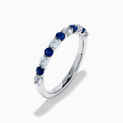 The Royale Bleu 14K White Gold Blue and White Sapphire Band Ring features alternating round blue and white sapphires on a sleek white gold band, shown against a white background.