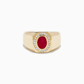 The Men's 14K Yellow Gold Bezel Halo Ruby and Diamond Signet Ring showcases an oval ruby center, encircled by a halo of white diamonds, all set in yellow gold against a white background.