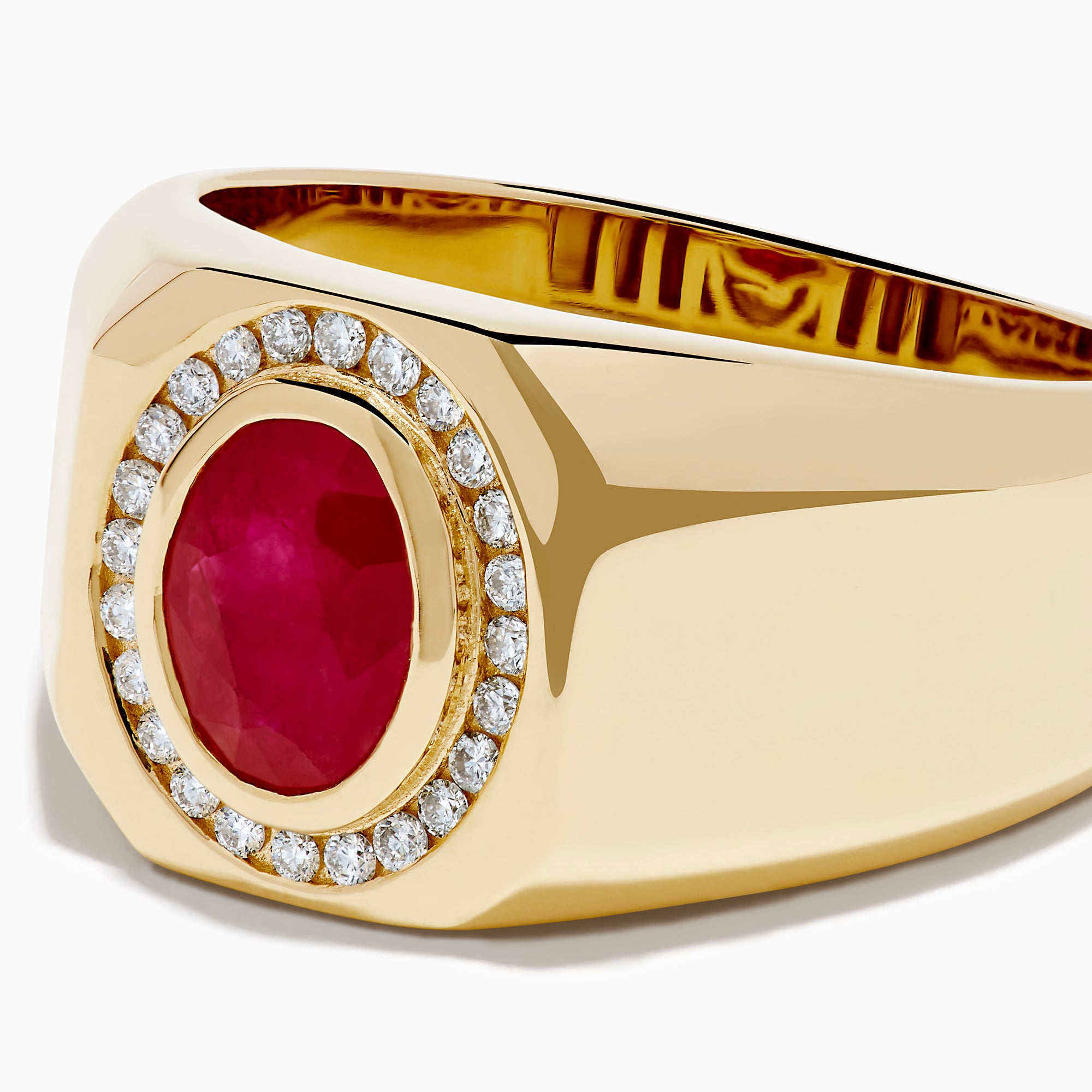 The Men's 14K Yellow Gold Bezel Halo Ruby and Diamond Signet Ring showcases an oval ruby center, encircled by a halo of white diamonds, all set in yellow gold against a white background.