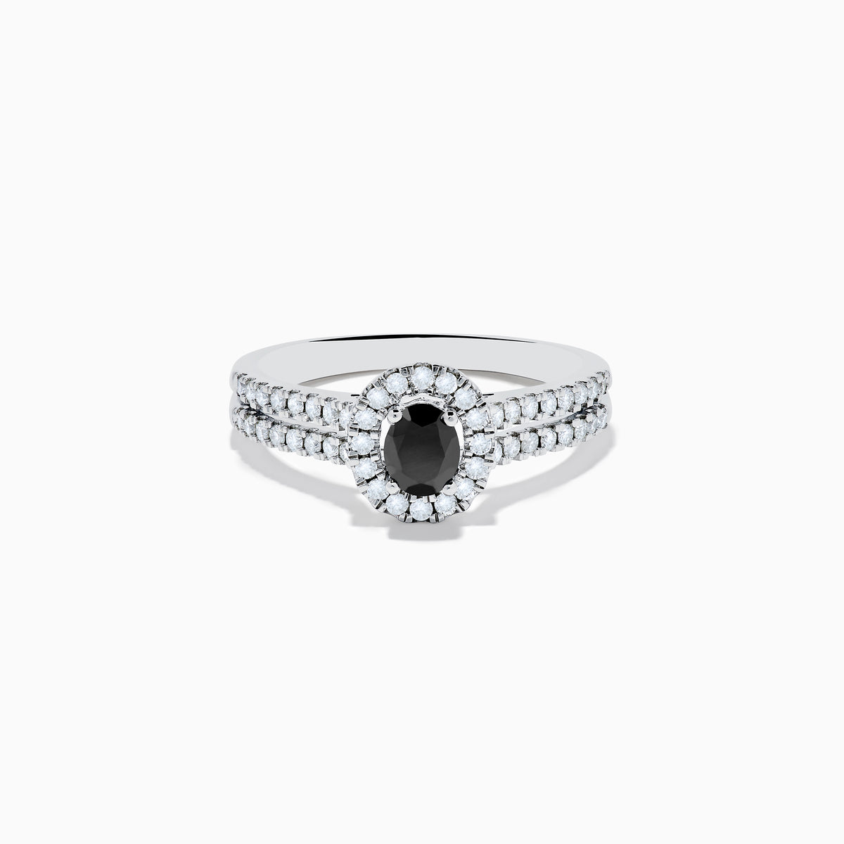The 14K White Gold White and Black Diamond Halo Ring features an oval black center stone, a halo of white diamonds, and additional diamonds set along its split shank band.