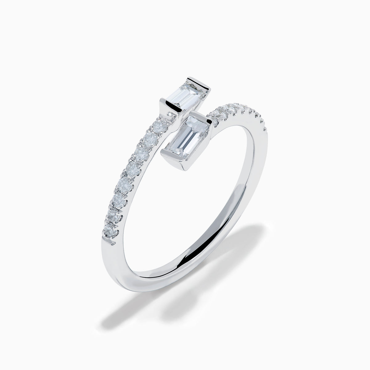 The 14K White Gold Diamond Bypass Ring features two rectangular baguette-cut diamonds at each end and a row of small round diamonds along the band, beautifully set against a white background.