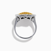 The Canare 18K Two Tone Gold Yellow Diamond Heart Ring, featuring a yellow diamond center with clear white stones on a silver band, is displayed against a white background.