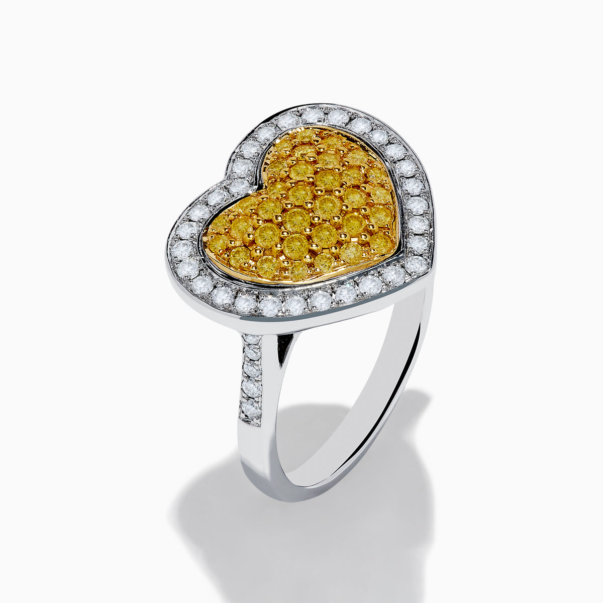 The Canare 18K Two Tone Gold Yellow Diamond Heart Ring, featuring a yellow diamond center with clear white stones on a silver band, is displayed against a white background.