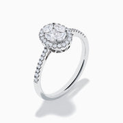 The Classique 14K White Gold Diamond Cluster Ring features an oval center diamond haloed by smaller diamonds, plus additional diamonds along its elegant band.