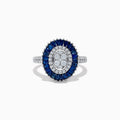 The Royal Bleu 14K White Gold Sapphire and Diamond Ring showcases an oval diamond cluster center, haloed by blue sapphires and accented with diamonds on the shoulders.