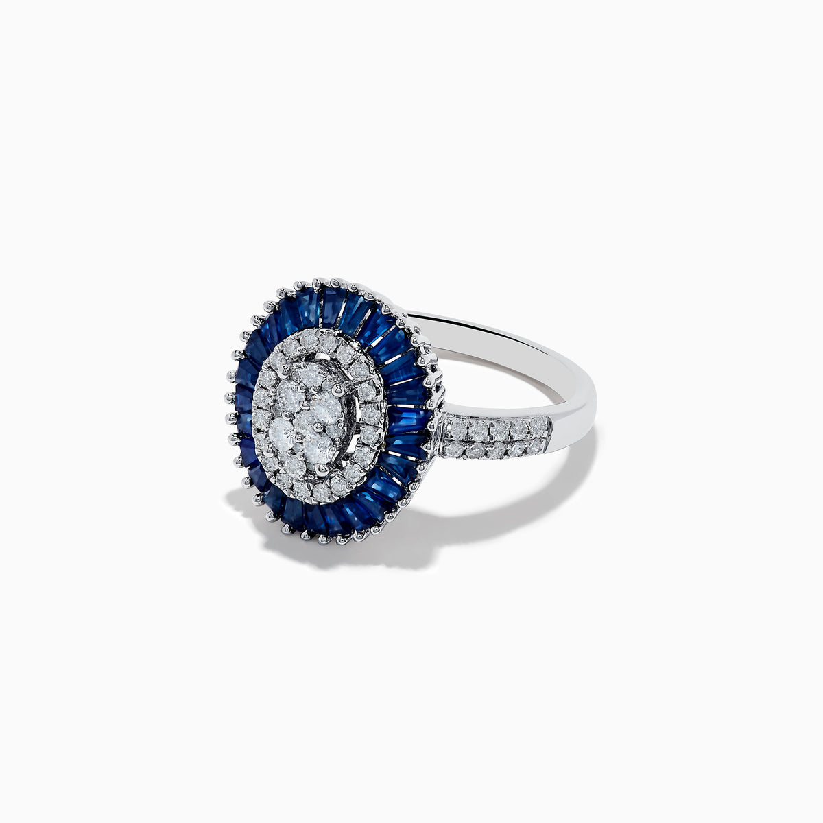 The Royal Bleu 14K White Gold Sapphire and Diamond Ring showcases an oval diamond cluster center, haloed by blue sapphires and accented with diamonds on the shoulders.