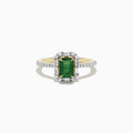 The 14K Yellow Gold Emerald and Diamond Ring features an emerald-cut green gemstone at the center, surrounded by round diamonds and enhanced with additional diamonds on the band.