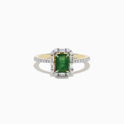 The 14K Yellow Gold Emerald and Diamond Ring features an emerald-cut green gemstone at the center, surrounded by round diamonds and enhanced with additional diamonds on the band.