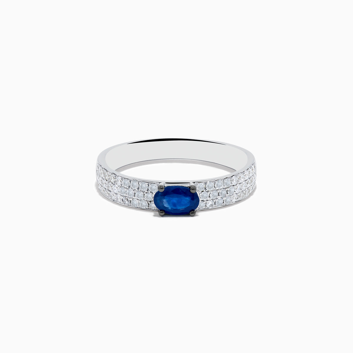 The Royal Bleu 14K White Gold Sapphire and Diamond Ring showcases an oval blue sapphire centerpiece with rows of small diamonds along the band, all set against a plain white background.