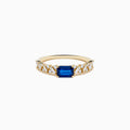 The 14K Yellow Gold Sapphire and Diamond Ring features a square-cut sapphire center with baguette and round-cut diamonds on the band, shown against a white background.