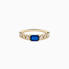 The 14K Yellow Gold Sapphire and Diamond Ring features a square-cut sapphire center with baguette and round-cut diamonds on the band, shown against a white background.