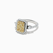 The Canare` 14K Two Tone Gold White and Yellow Diamond Ring showcases a cluster of yellow diamonds at the center, surrounded by white diamonds on a rectangular band.
