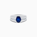 The Mens 14K White Gold Sapphire and Diamond Ring features a large oval blue sapphire at the center, accented on each side by rows of small round white diamonds set into the stylish band.