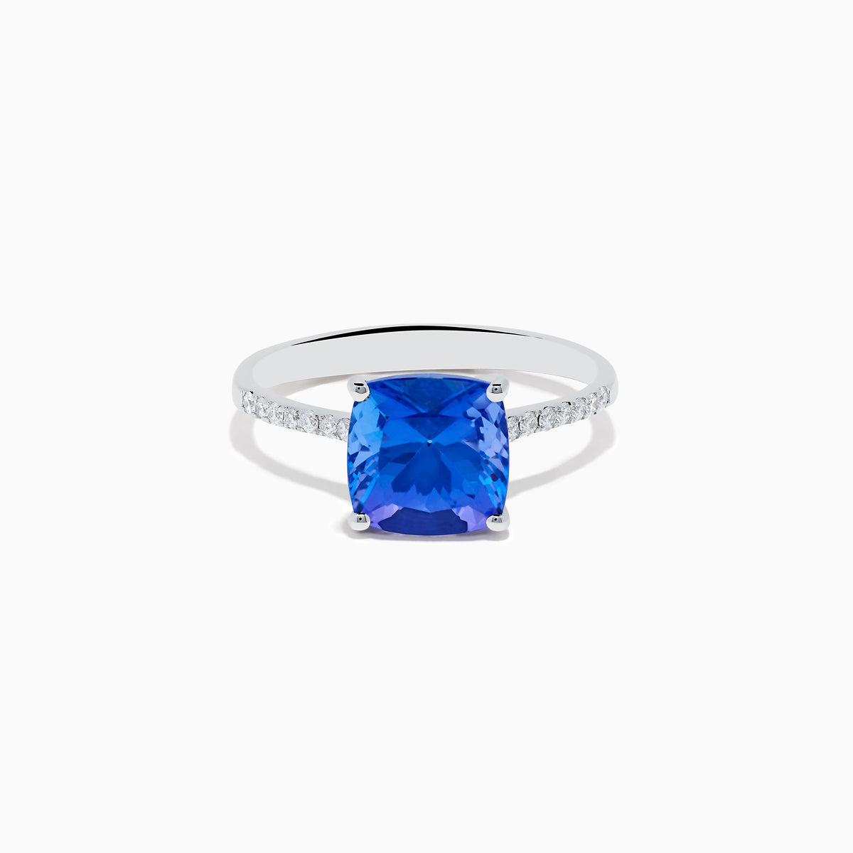 The Nahla 14K White Gold Cushion Tanzanite and Diamond Ring features a large cushion-cut blue tanzanite, flanked by sparkling diamonds along the band, shown on a white background.