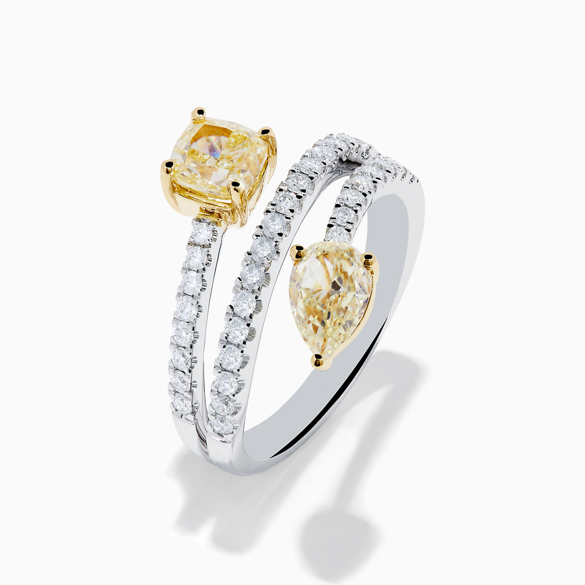 The Canare 18K Two Tone White and Yellow Diamond Bypass Ring features a spiral design with a row of small white diamonds, highlighted by yellow cushion-cut and pear-shaped diamonds set in yellow gold prongs.