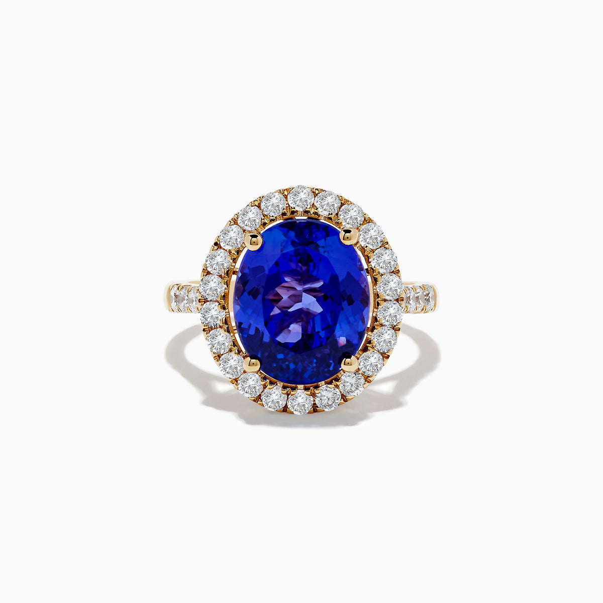 The Nahla Siri 14K Yellow Gold Tanzanite and Diamond Ring features a large oval blue tanzanite center stone encircled by a halo of small round white diamonds, displayed on a plain white background.