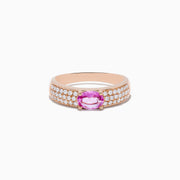 The 14K Rose Gold Pink Sapphire and Diamond Ring showcases a central oval pink sapphire, accented by rows of sparkling round diamonds along the band.