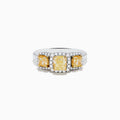 The Canare 18K Two Tone White and 3 Stone Yellow Diamond Ring showcases three rectangular yellow diamonds, each haloed with sparkling diamonds, set on a diamond-studded white gold band.