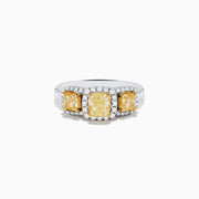 The Canare 18K Two Tone White and 3 Stone Yellow Diamond Ring showcases three rectangular yellow diamonds, each haloed with sparkling diamonds, set on a diamond-studded white gold band.
