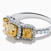 The Canare 18K Two Tone White and 3 Stone Yellow Diamond Ring showcases three rectangular yellow diamonds, each haloed with sparkling diamonds, set on a diamond-studded white gold band.