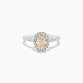 The Canare 18K Two Tone White and Yellow Diamond Ring features an oval yellow diamond center, surrounded by a halo of round white diamonds with extra diamonds adorning the band.