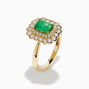 The Brasilica 14K Yellow Gold Emerald and Diamond Double Halo Ring showcases a rectangular green emerald at the center, accented by two rows of sparkling round white diamonds in an elegant scalloped halo design.