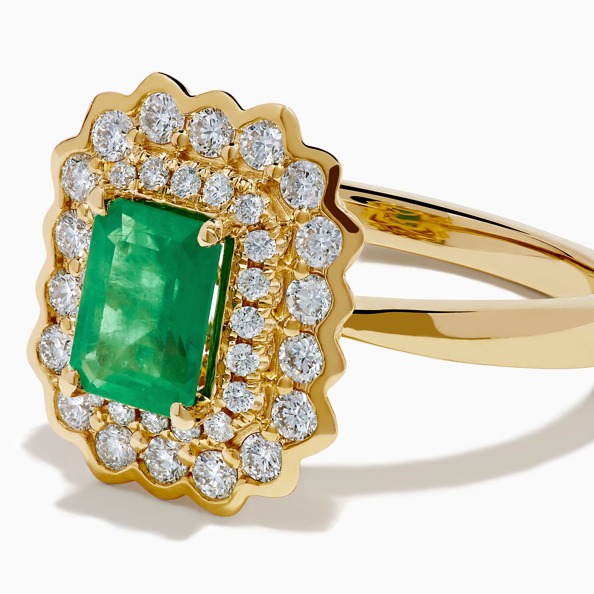 The Brasilica 14K Yellow Gold Emerald and Diamond Double Halo Ring showcases a rectangular green emerald at the center, accented by two rows of sparkling round white diamonds in an elegant scalloped halo design.