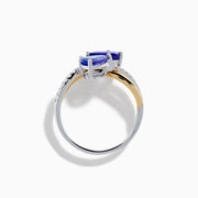 The Nahla 14K Two Tone Gold Tanzanite and Diamond Bypass Ring features two pear-shaped tanzanites and a curved band with sparkling white diamonds, displayed against a white background.