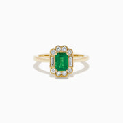 The 14K Yellow Gold Emerald and Diamond Halo Vintage Ring features an emerald-cut green center stone, accented by round and baguette white diamonds in a vintage halo setting.