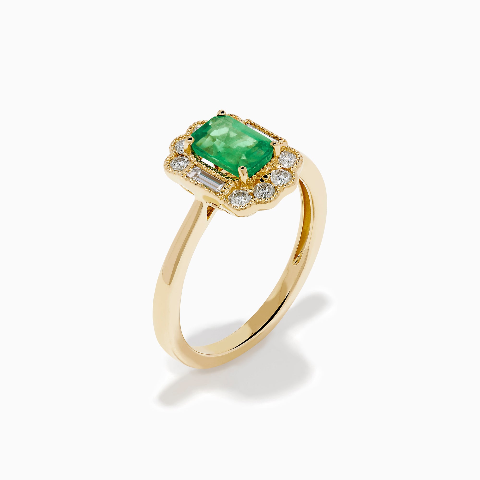 The 14K Yellow Gold Emerald and Diamond Halo Vintage Ring features an emerald-cut green center stone, accented by round and baguette white diamonds in a vintage halo setting.
