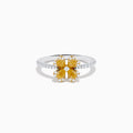 The Canare 14K White & Yellow Gold Yellow Diamond Flower Ring features a four-petal design with yellow diamonds and a central clear stone, set on a slim band accented with small white stones.