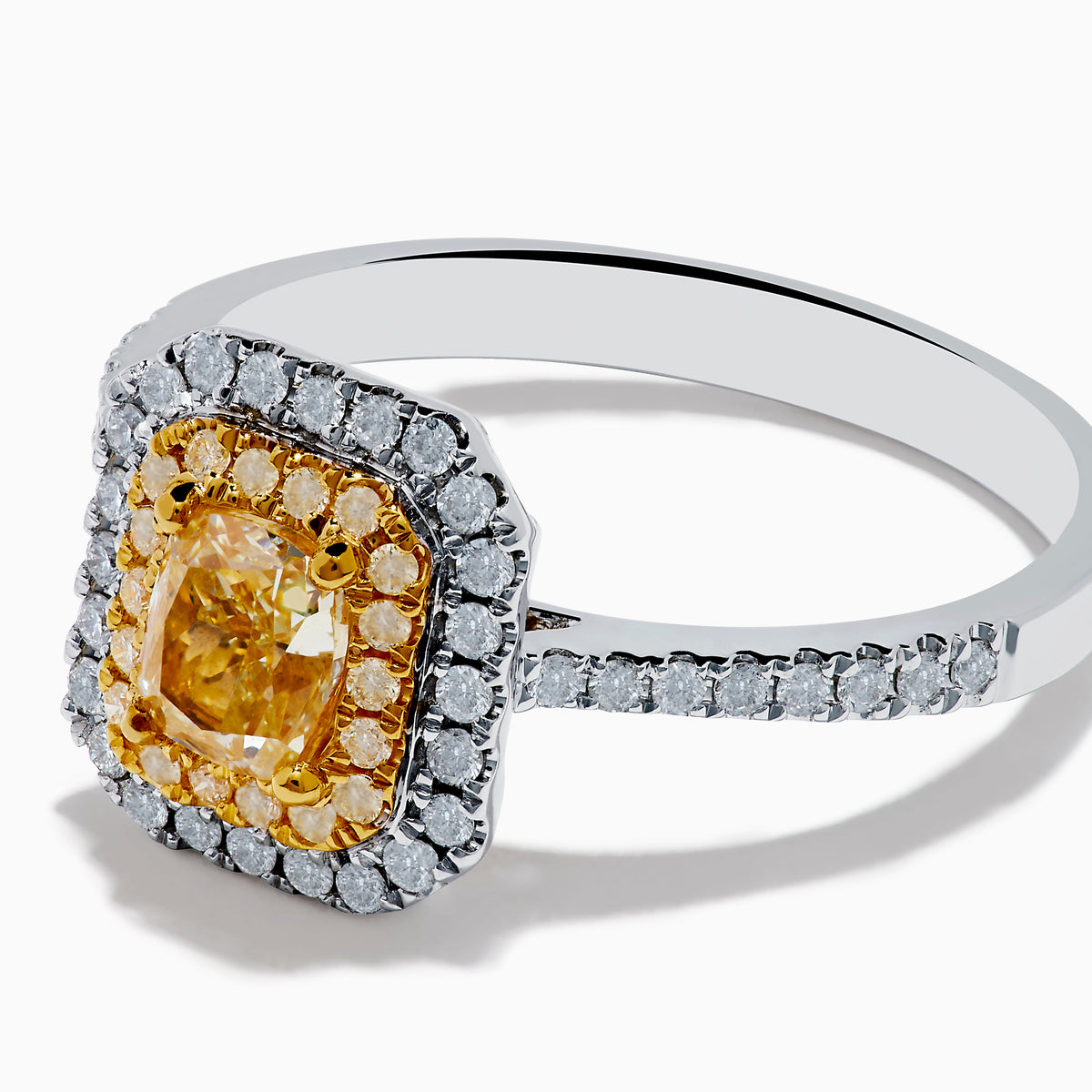 The Canare 18K Two Tone Gold White and Yellow Diamond Ring features a large rectangular yellow gemstone, double halo of white diamonds, and diamond accents on the elegant band.