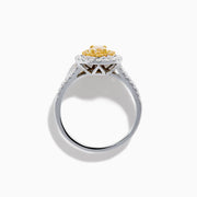 The Canare 18K Two Tone Gold White and Yellow Oval Diamond Split Shank Ring showcases an oval yellow diamond center with a double halo of white diamonds and a diamond-accented split shank, displayed on a plain white background.