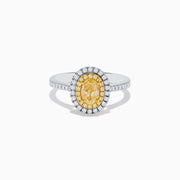 The Canare 18K Two Tone Gold White & Yellow Diamond Ring features a central oval yellow gemstone, accented by a halo of white diamonds and additional diamonds set along the band.