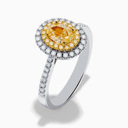 The Canare 18K Two Tone Gold White & Yellow Diamond Ring features a central oval yellow gemstone, accented by a halo of white diamonds and additional diamonds set along the band.