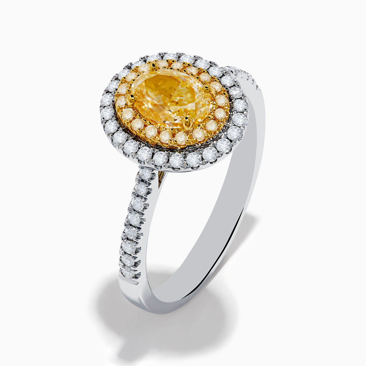A close-up of the Canare 18K Two Tone Gold White & Yellow Diamond Ring, highlighting its oval yellow center stone encircled by two halos of white diamonds and additional diamonds set along the elegant silver band.