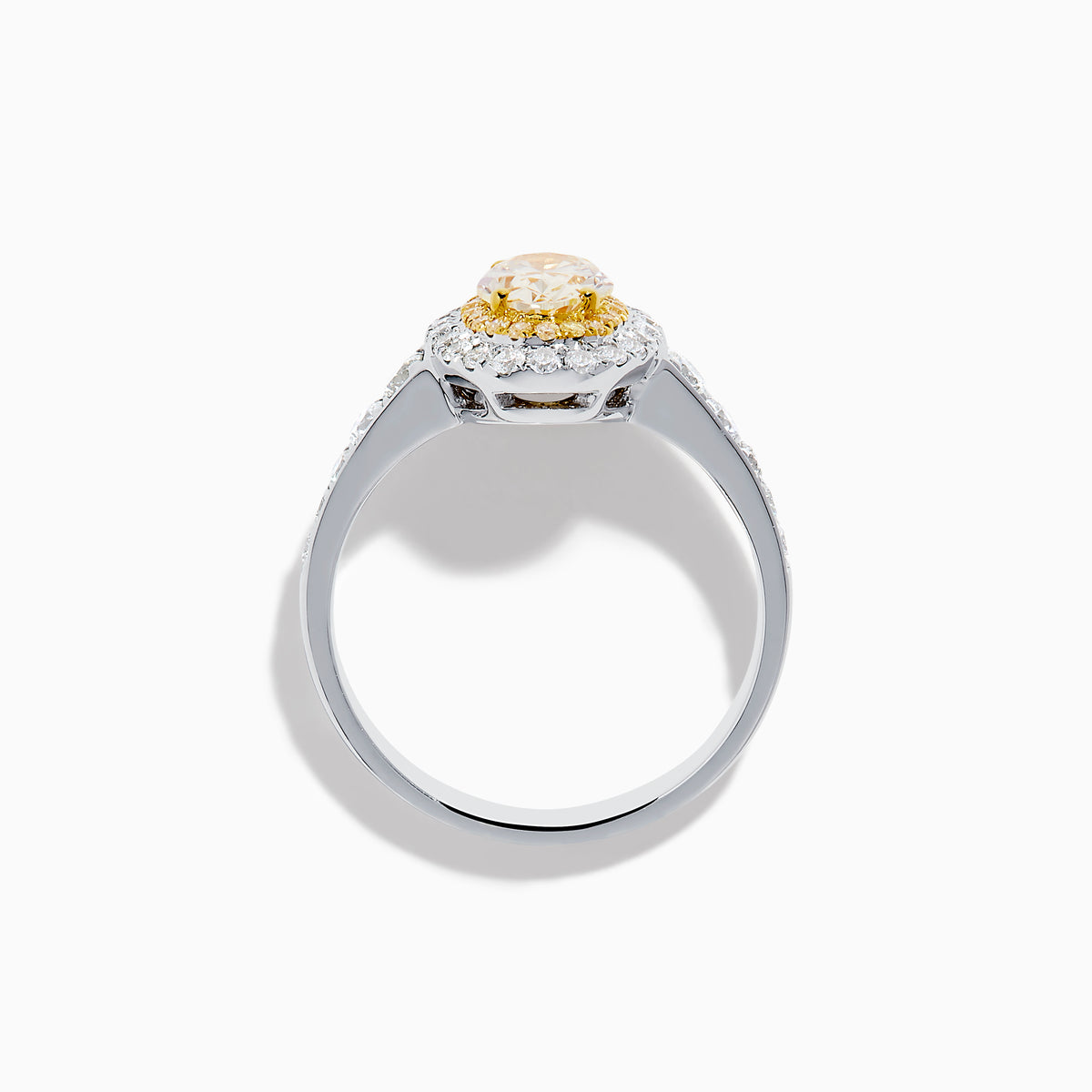 The Canare 18K Two Tone Gold White and Yellow Oval Diamond Ring features a large yellow diamond at the center, a halo of small round white diamonds, and additional diamonds set along the elegant band.