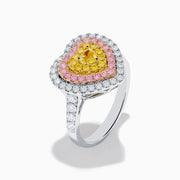 The Trio 18K Tri Color Gold White, Pink, and Yellow Diamond Heart Ring features a yellow diamond center, surrounded by pink and white diamonds on an 18K gold band for a luxurious finish.
