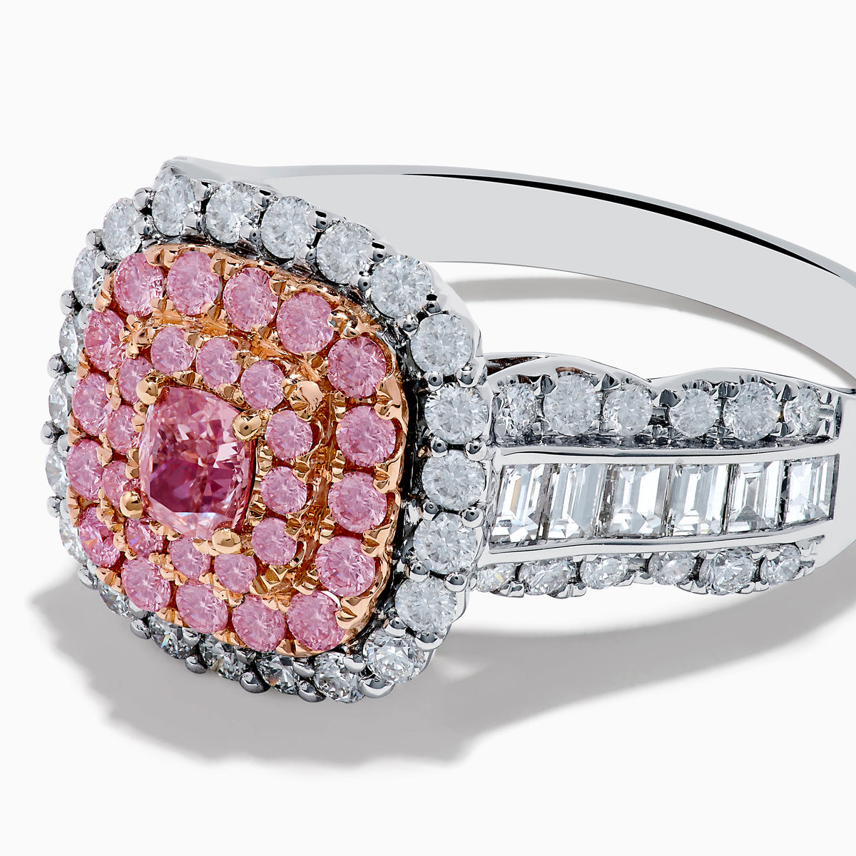 The 18K Two Tone Gold White and Pink Diamond Ring features a cushion-shaped cluster of pink diamonds at the center, encircled by a double halo of white diamonds, with more diamonds set along the band.