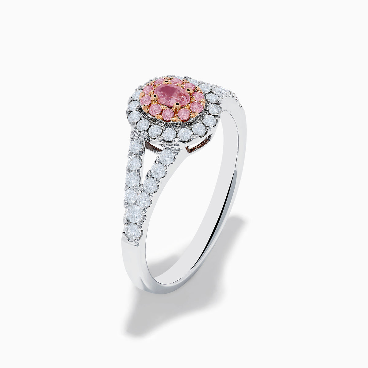 The 18K Two Tone Gold White and Pink Diamond Ring features an oval pink center gemstone, a halo of white and pink stones, and additional white stones set along the split band.