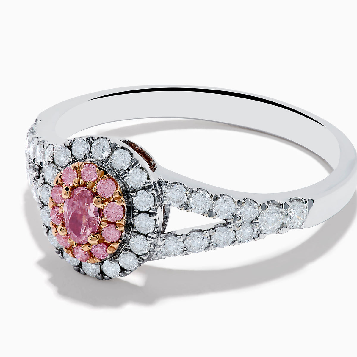 The 18K Two Tone Gold White and Pink Diamond Ring features an oval pink center gemstone, a halo of white and pink stones, and additional white stones set along the split band.