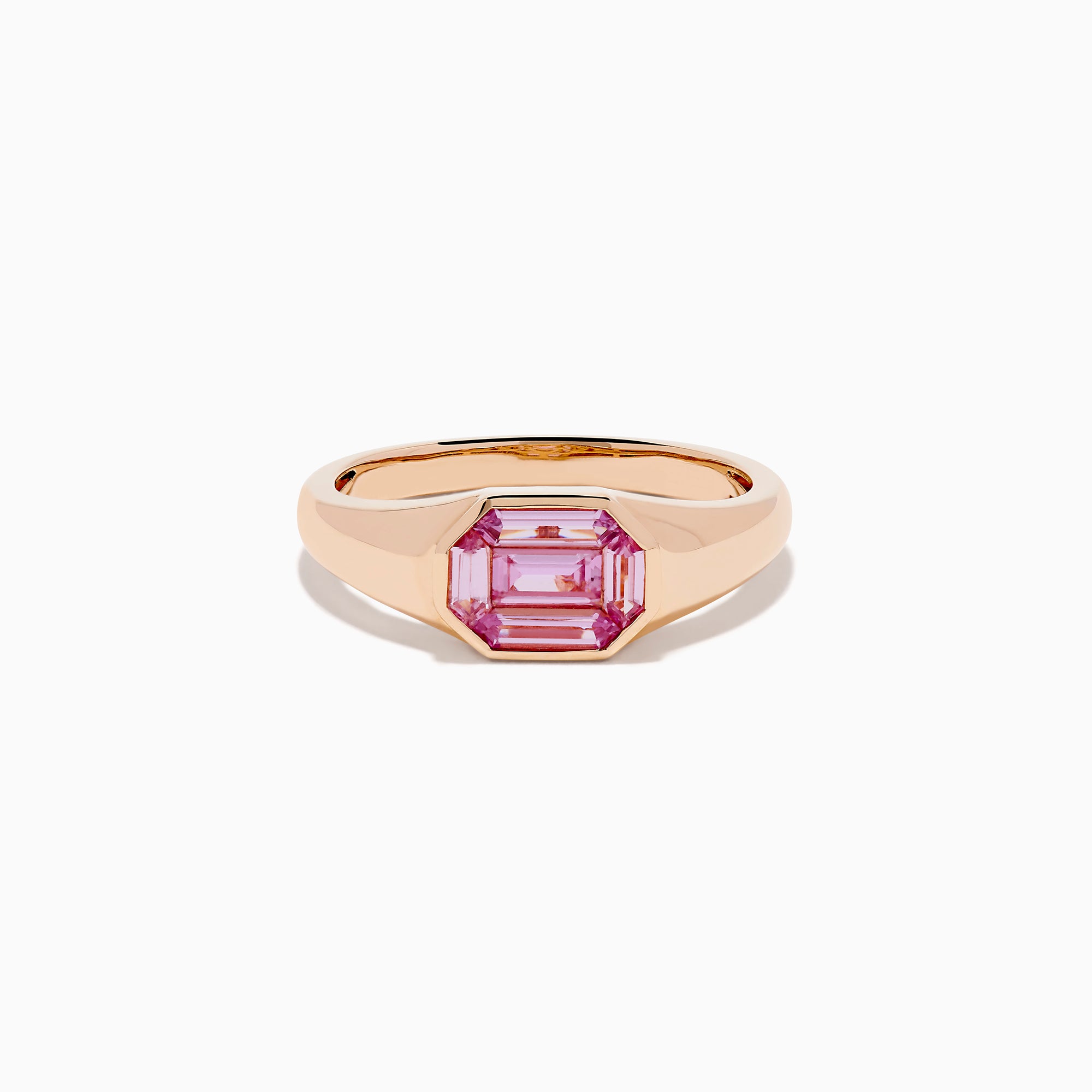 The 14K Rose Gold Bezel Set Pink Sapphire Ring showcases an emerald-cut pink sapphire in a bezel setting, presented on a white background.