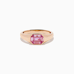 The 14K Rose Gold Bezel Set Pink Sapphire Ring showcases an emerald-cut pink sapphire in a bezel setting, presented on a white background.