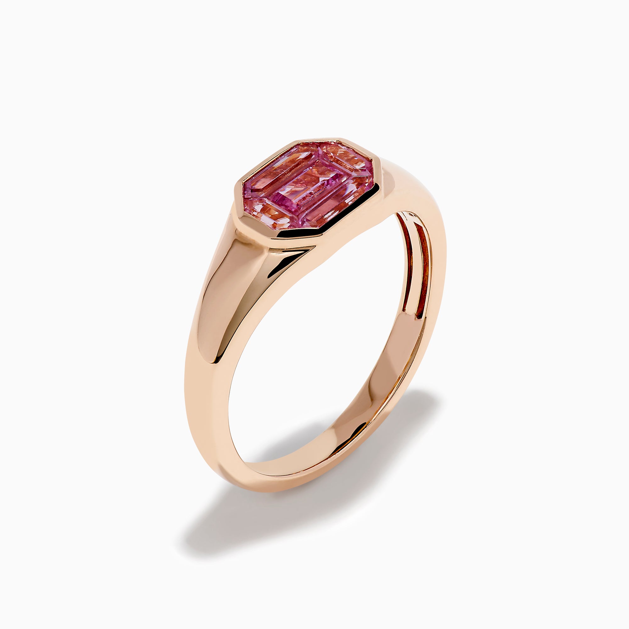 The 14K Rose Gold Bezel Set Pink Sapphire Ring showcases an emerald-cut pink sapphire in a bezel setting, presented on a white background.