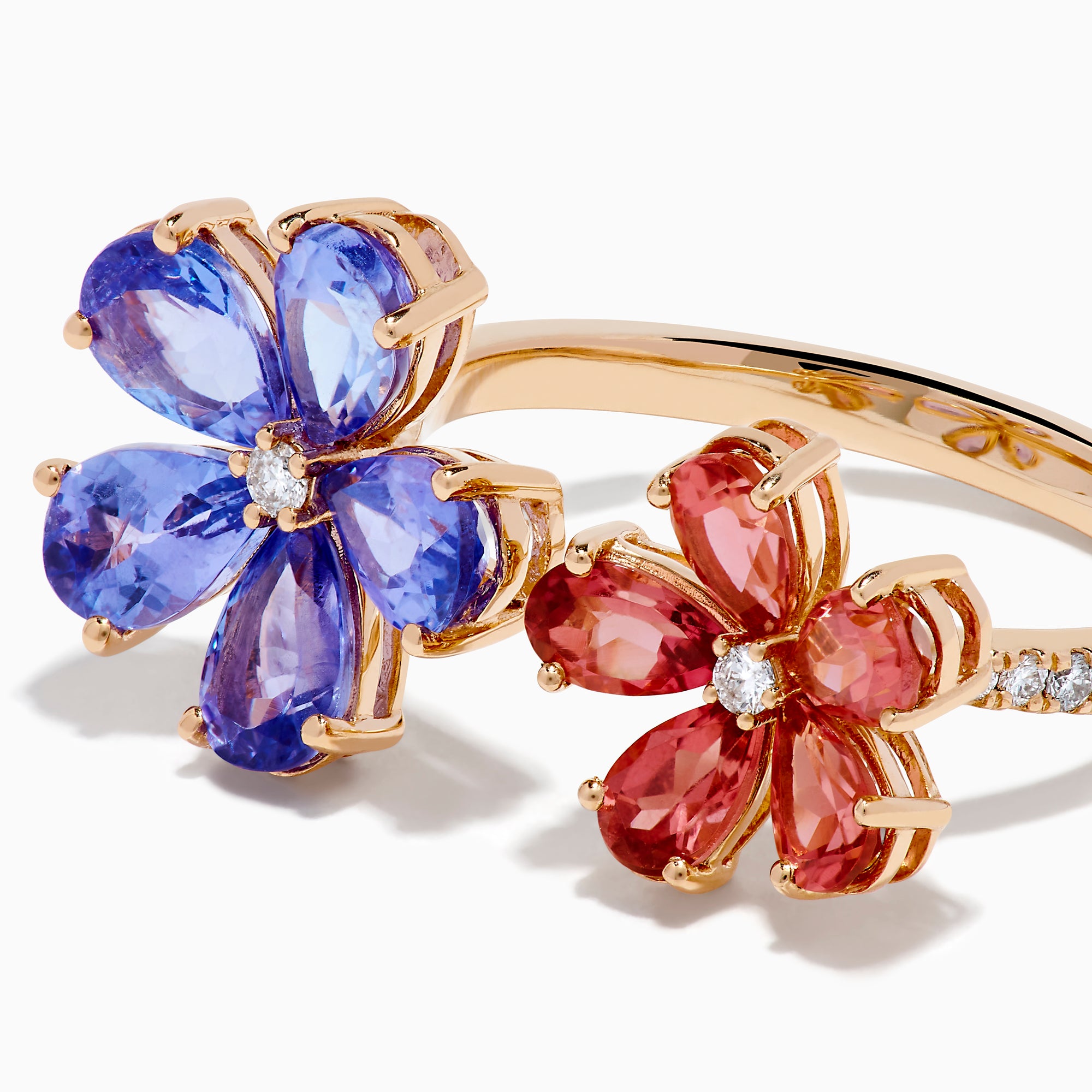 The 14K Rose Gold Tanzanite, Tourmaline and Diamond Floral Ring features two flower designs with tanzanite blue and pink tourmaline petals, each centered by a sparkling diamond, all set against a white background.