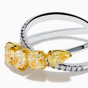 The 18K Two Tone White & Yellow Diamond Criss Cross Ring features a split silver band with five yellow pear-shaped stones on one side and white diamonds on the other, shown against a white background.