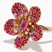 The Nature 14K Rose Gold Pink Sapphire and Diamond Flower Ring features a floral design with five petals, small pink and red gemstones, a central oval pink sapphire, and shimmering rose gold outlining for added sparkle.