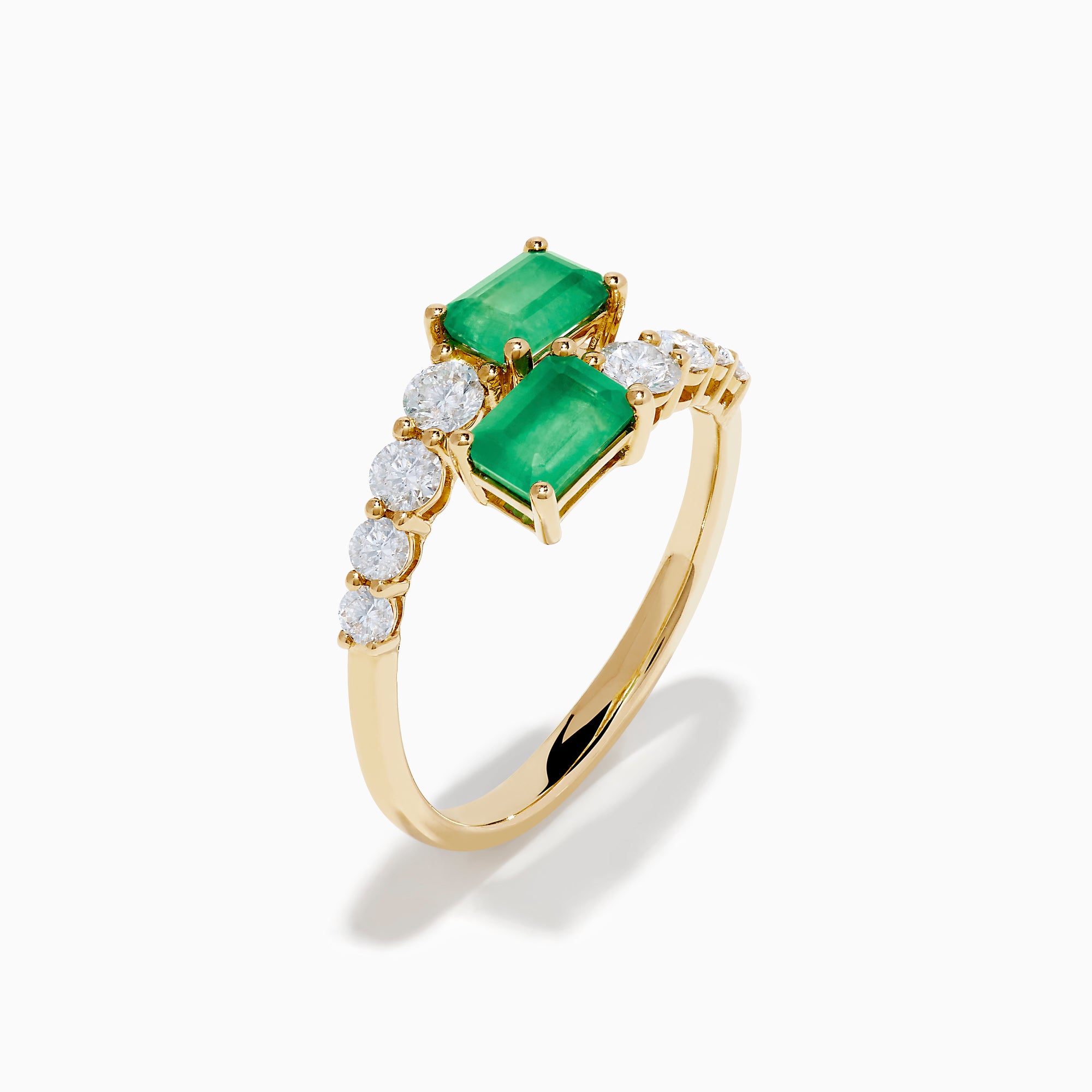 The 14K Yellow Gold Diamond and Emerald Bypass Ring features two rectangular green emeralds and rows of sparkling round white diamonds on each side in an open band design, set against a white background.