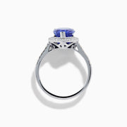 The Nahla 14K White Gold Tanzanite and Diamond Halo Ring features a pear-shaped tanzanite surrounded by diamonds on a slender, diamond-encrusted band, beautifully displayed on a white background.