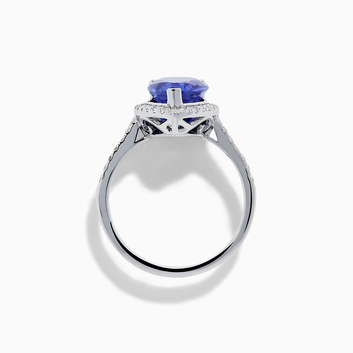 The Nahla 14K White Gold Tanzanite and Diamond Halo Ring features a pear-shaped tanzanite surrounded by diamonds on a slender, diamond-encrusted band, beautifully displayed on a white background.